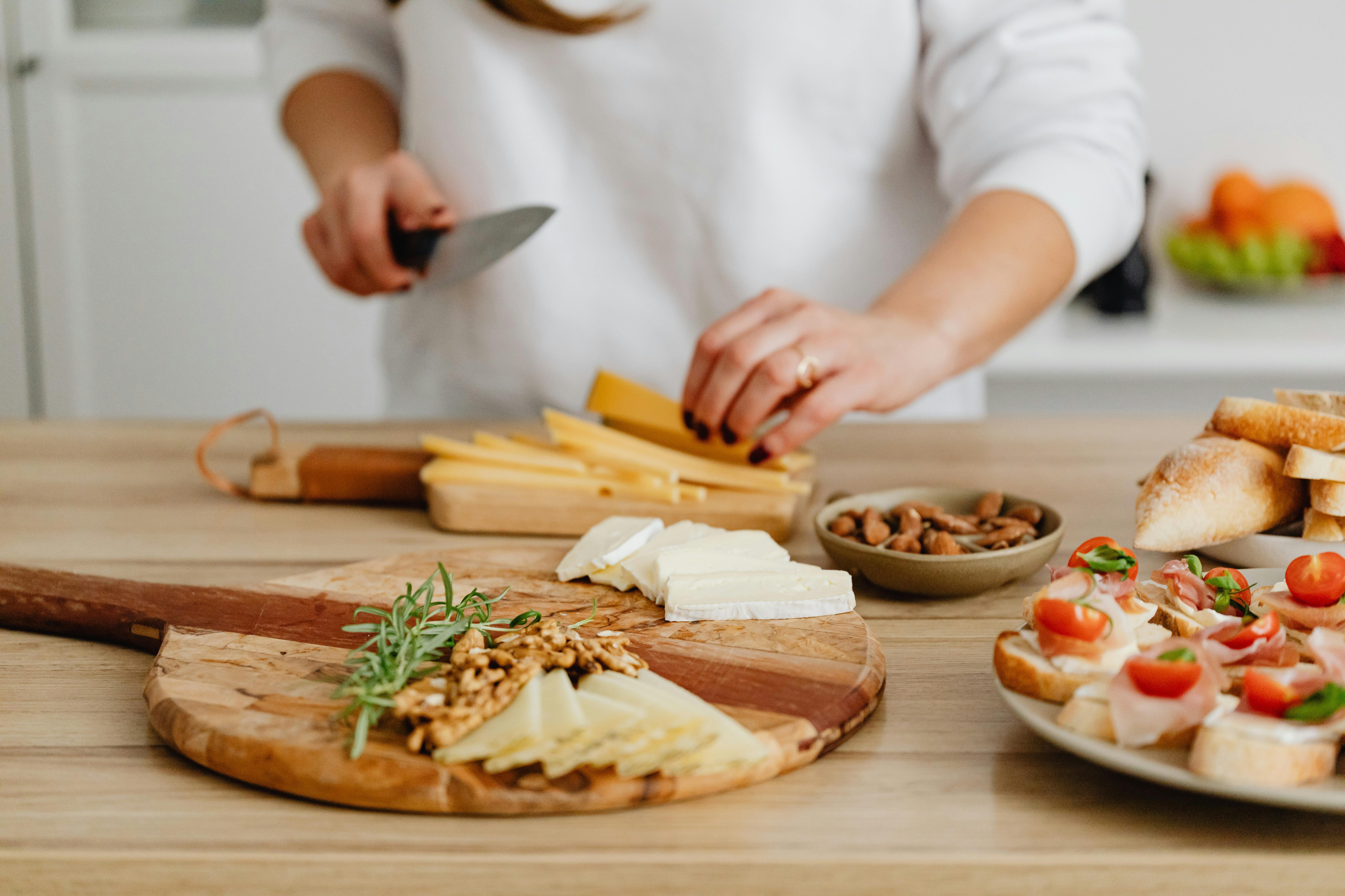 person slicing cheese on brown wooden chopping board