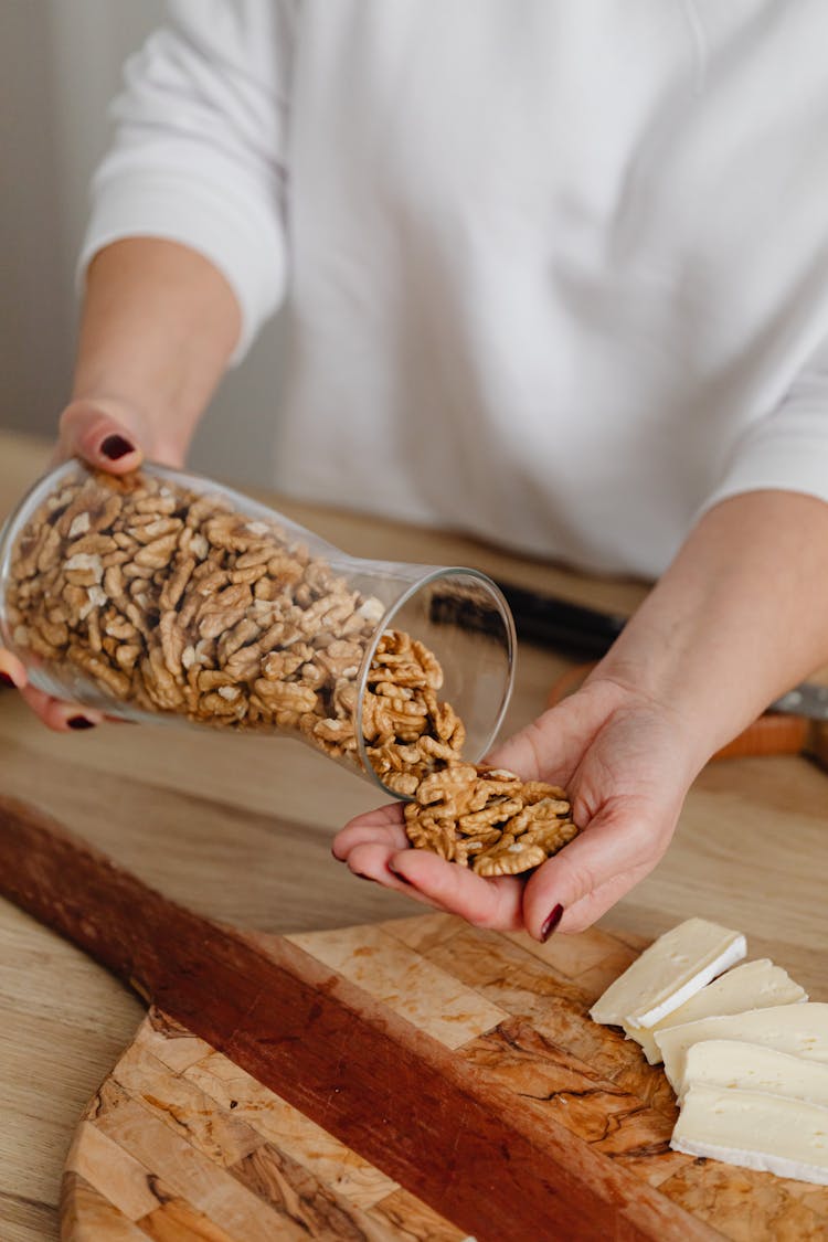 Person Holding Glass Jar With Walnuts