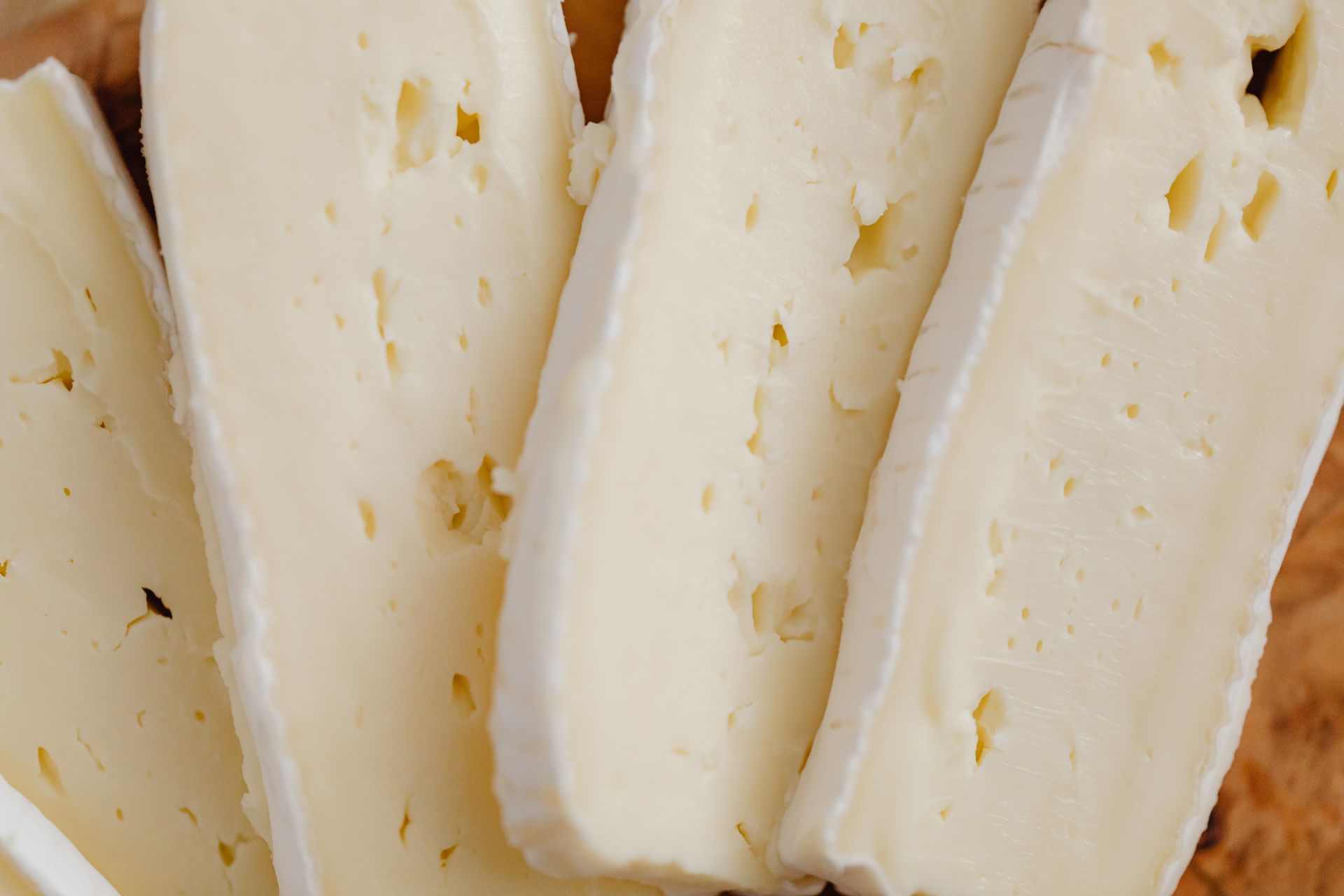 Close-up view of creamy cheese slices with a bloomy rind, perfect for culinary displays.