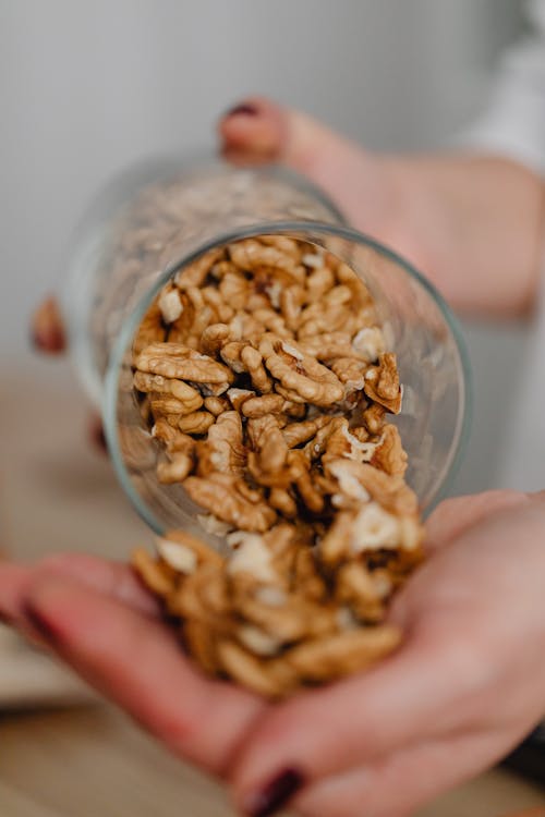 Free Close-Up Photo of a Person Pouring Walnuts Stock Photo