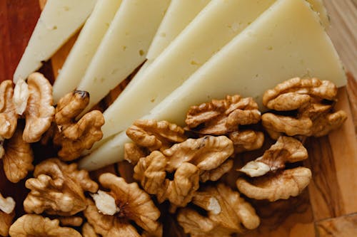 Free Sliced Cheese and Roasted Walnuts on Wooden Board Stock Photo