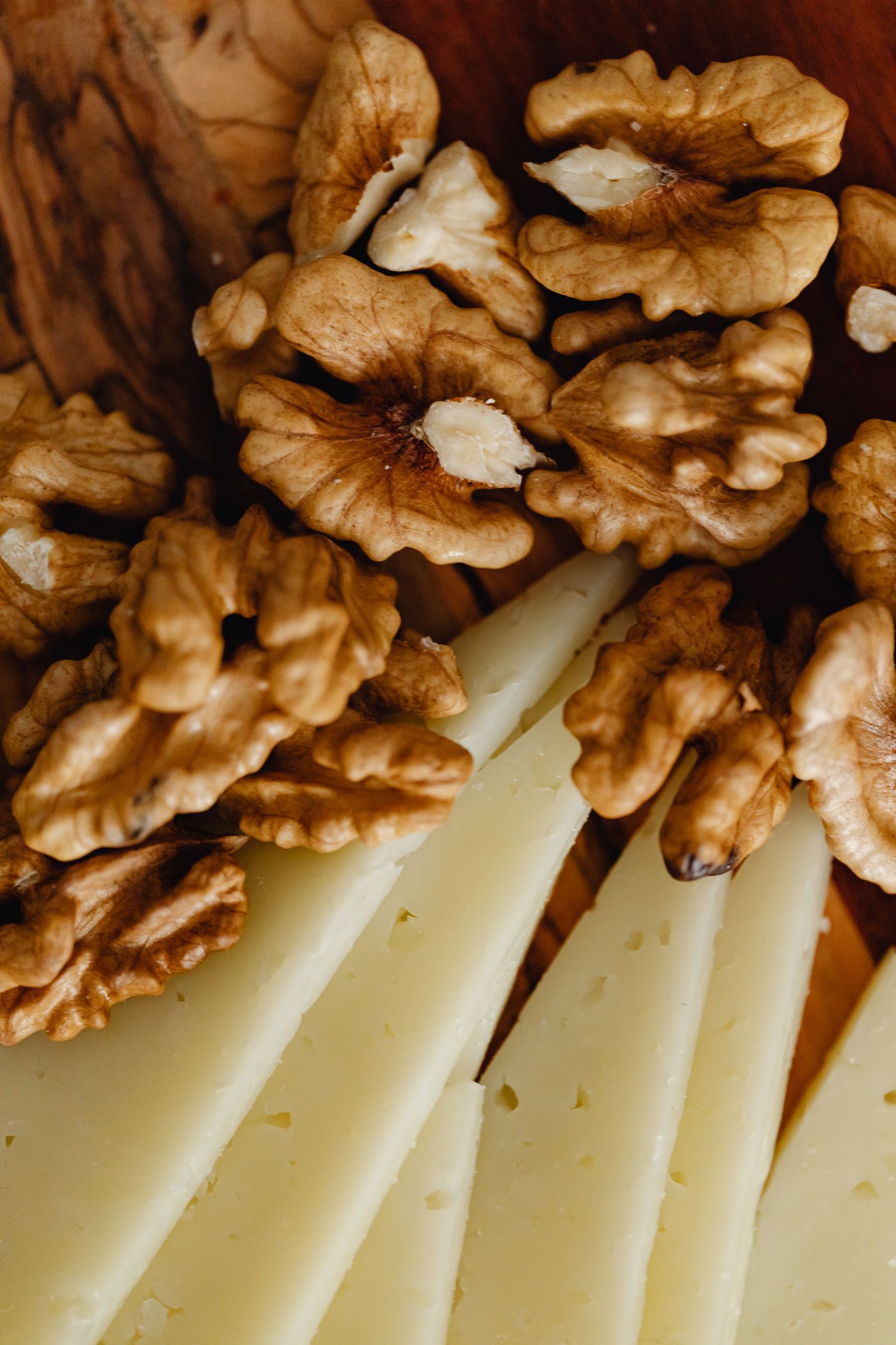 Wedges of aged Spanish sheep's milk cheese with walnuts on a wooden board, ready to pair with Rioja Gran Reserva