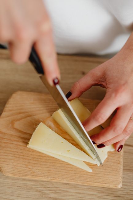 A block of provolone cheese with several slices cut, showing its pale ivory interior and smooth, slightly waxy rind.