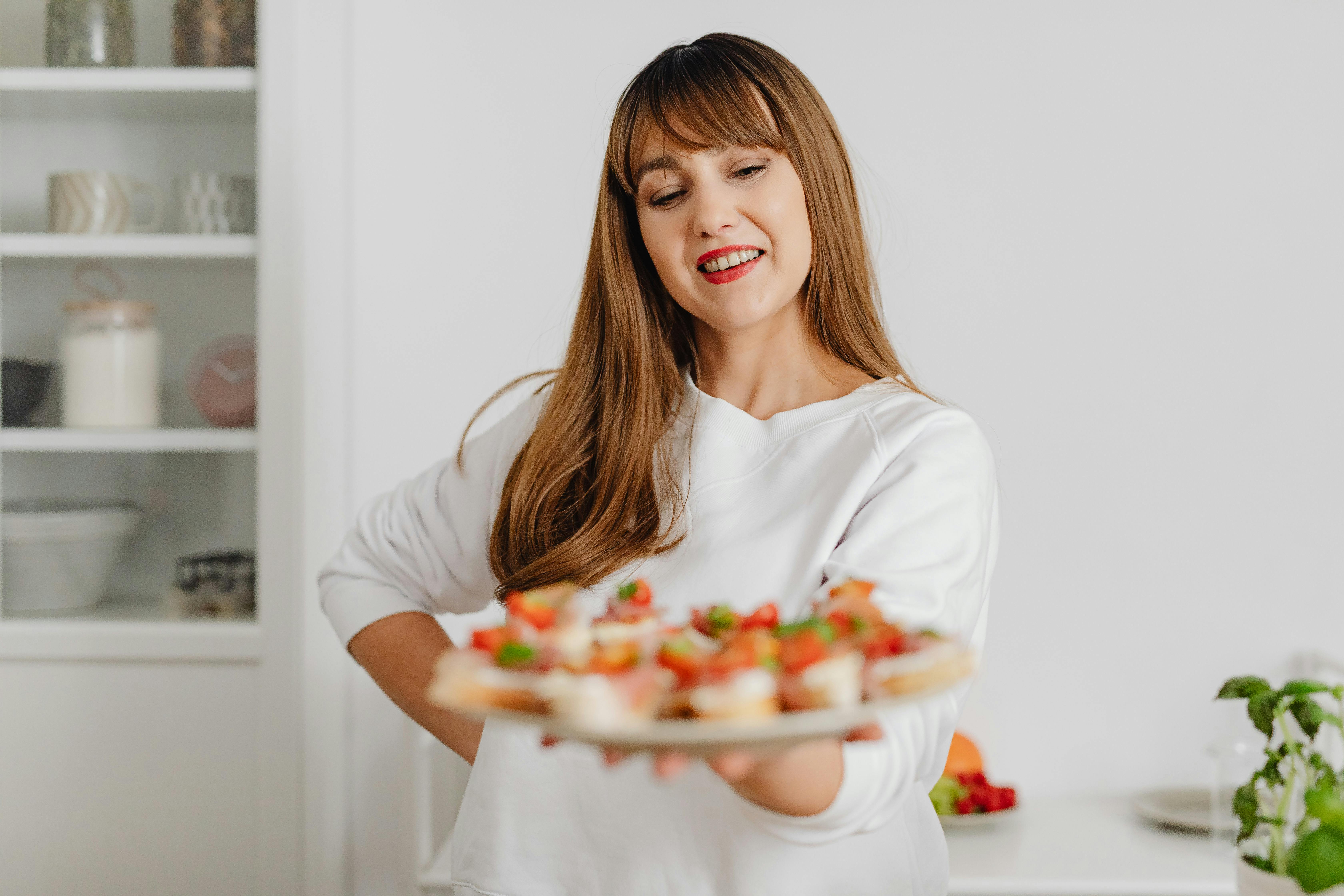 Woman in White Top Holding a Plate of Canapes