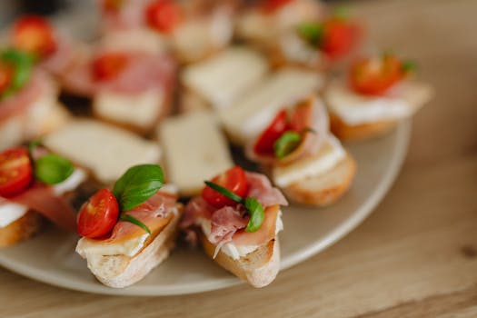 Delicious bruschetta appetizers with prosciutto, cheese, and cherry tomatoes on a serving platter.