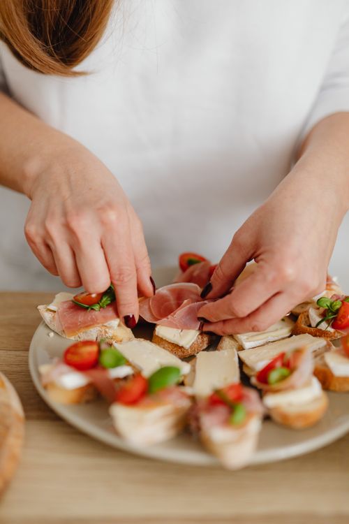 Free Close-up of a woman arranging tasty bruschettas with fresh ingredients. Stock Photo