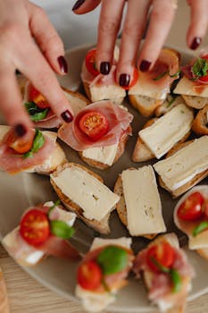 Close-up of hands preparing tasty bruschetta with cheese and prosciutto on a plate.
