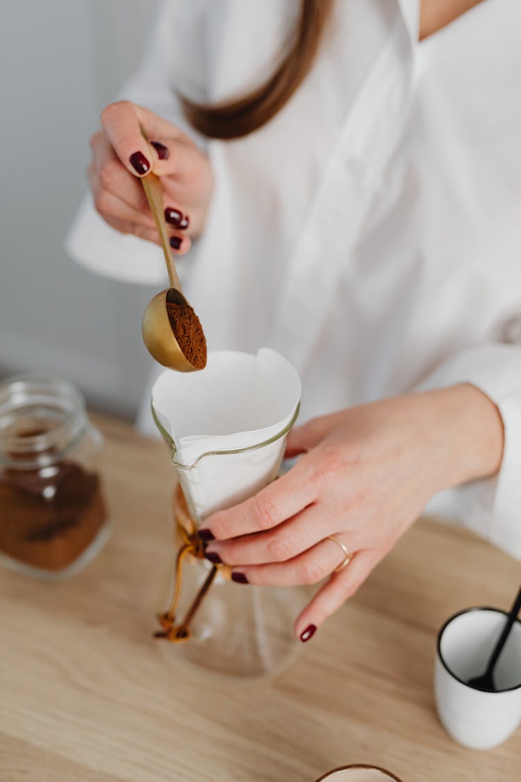 Woman Placing Coffee Powder Into A Glass Jar With Filter