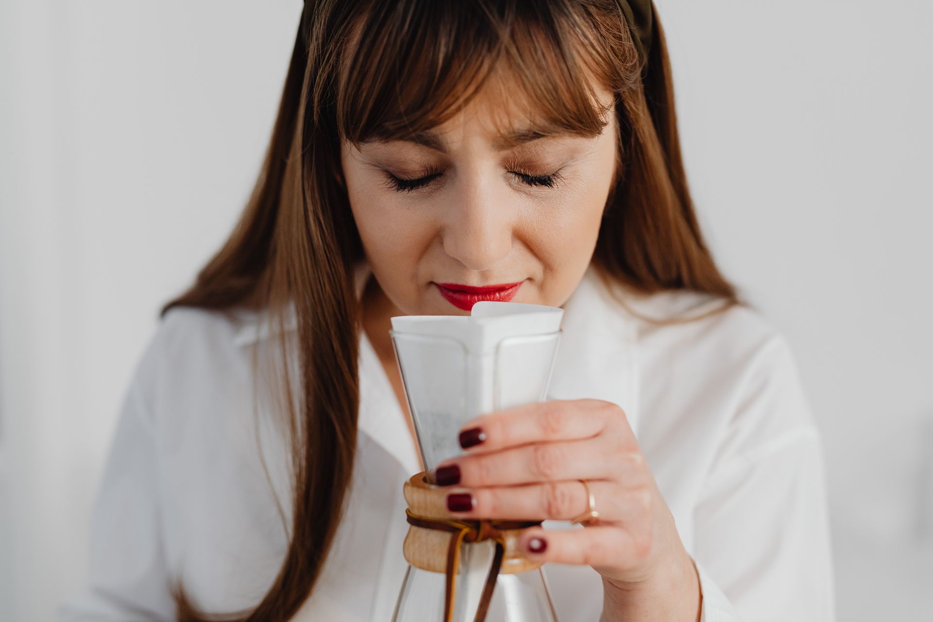 Woman in White Long Sleeve Shirt Smelling a Jar
