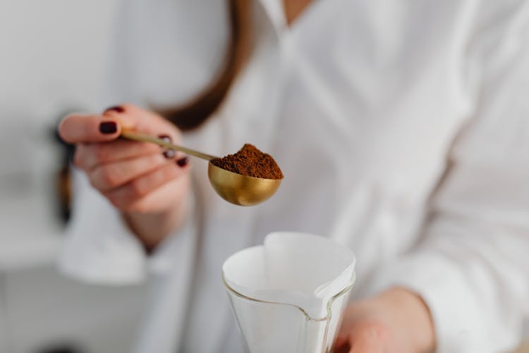 Hand Of A Woman Holding A Scoop Of Coffee Powder