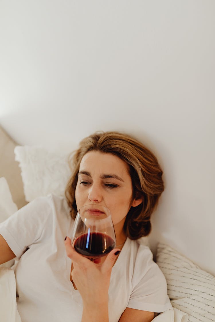 Woman Lying In Bed Drinking Wine