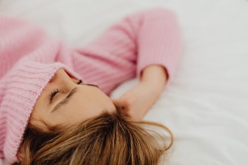 Free Woman in Sweater Lying on the Bed Stock Photo