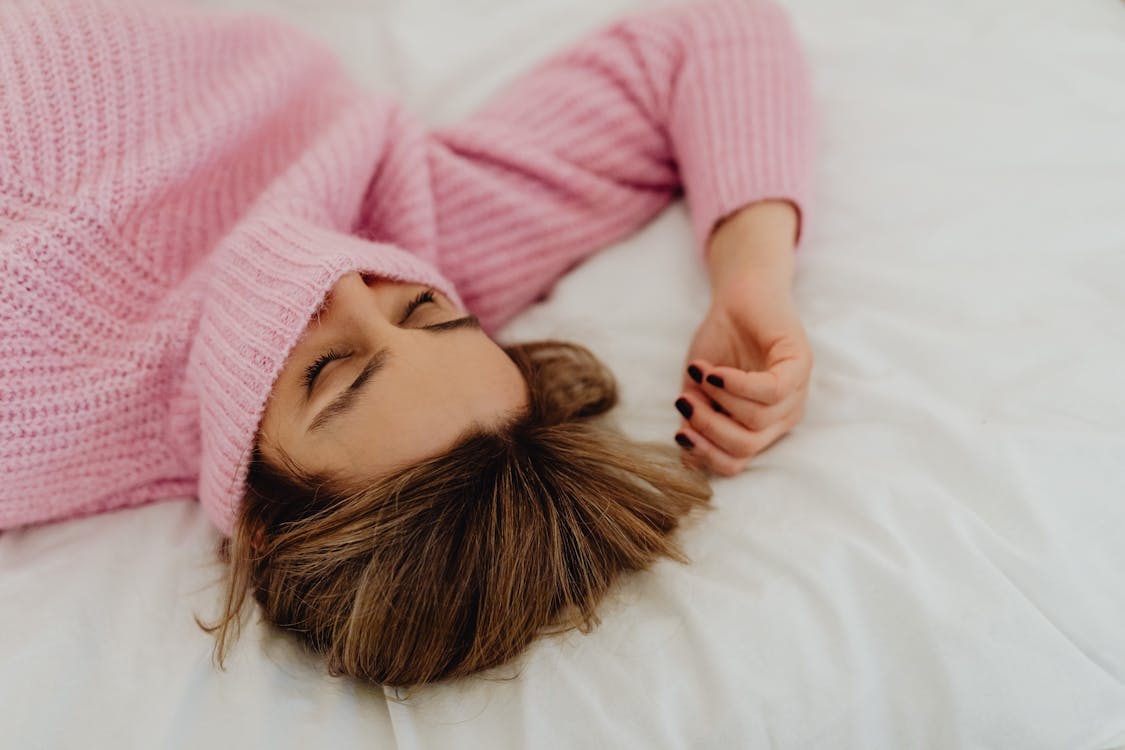 Free Woman in Pink Knit Sweater Lying on Bed Stock Photo
