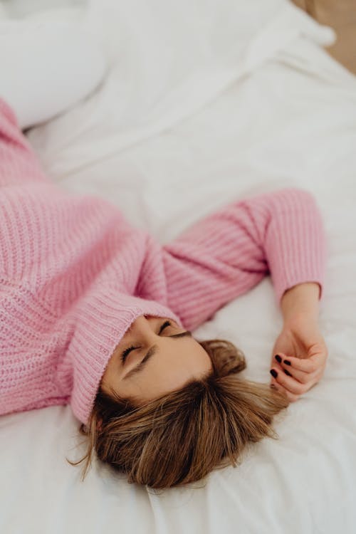 Free A Woman Wearing Turtle Neck Sweater Lying on the Bed Stock Photo