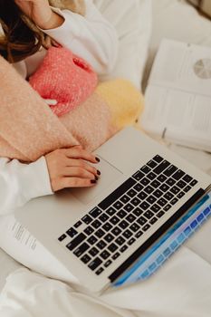 Woman working on a laptop while wrapped in a colorful blanket, promoting a cozy home workspace.