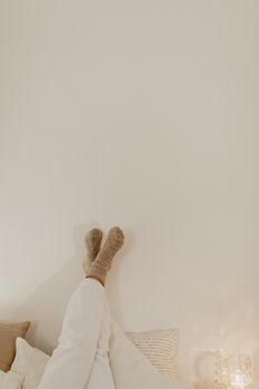 A peaceful scene of feet in socks resting against a wall with soft pillows.