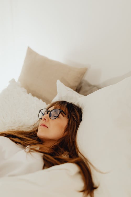 Free A Woman Lying in Bed with Eyeglasses  On Stock Photo