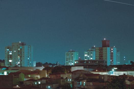 A tranquil cityscape at night showcasing high-rise buildings lit up against a clear sky.