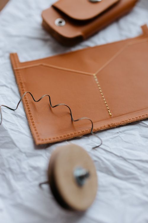 Free Close-up of a handcrafted leather project with sewing tools on crumpled paper. Stock Photo