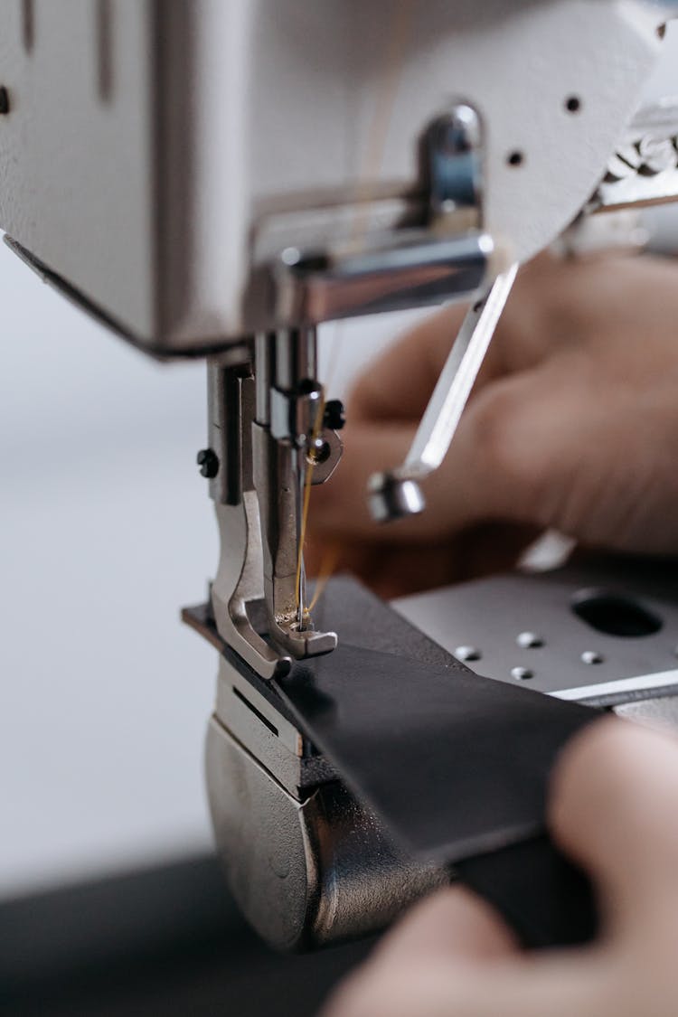 A Person Sewing A Black Leather Fabric