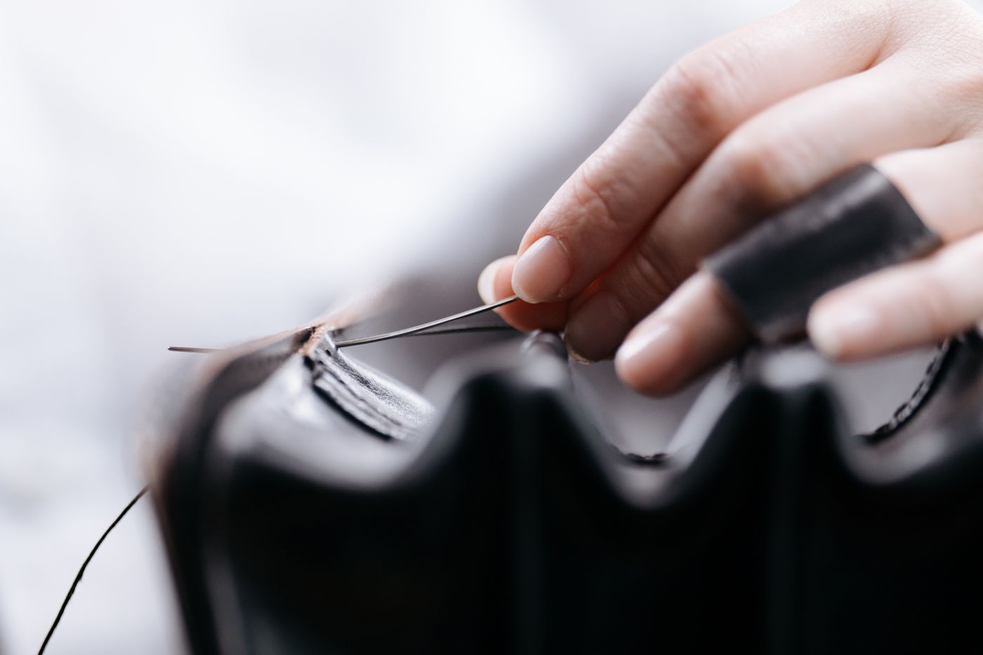 Handen stikken de rand van een leren schoen met gewaxt garen