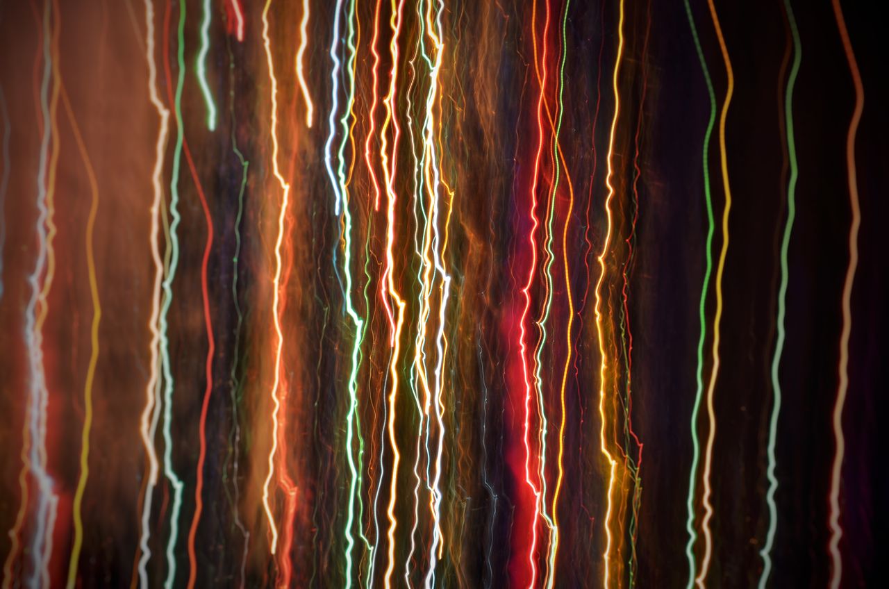 colorful light trails create an abstract pattern against a dark backgr