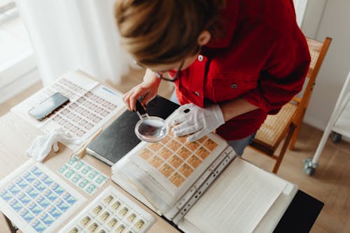 A Woman Using a Magnifying Glass on Postage Stamps