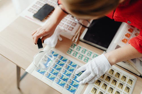 A Woman Using a Magnifying Glass on Postage Stamps