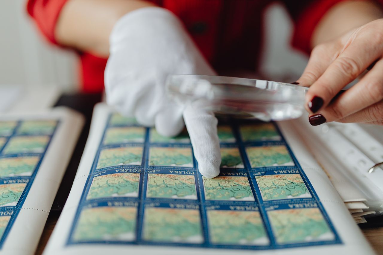 close up of a person inspecting vintage stamps with a magnifying glass