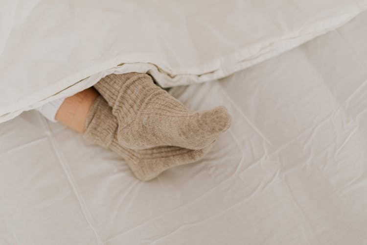 Person Wearing Beige Socks On White Textile