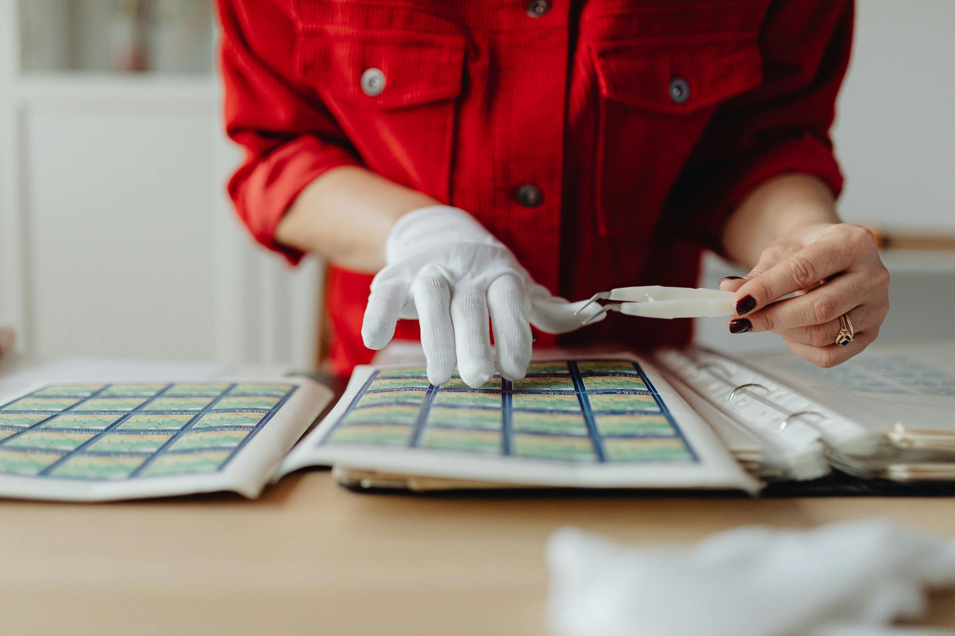 A Person with a Postage Stamp Collection Holding Tweezers