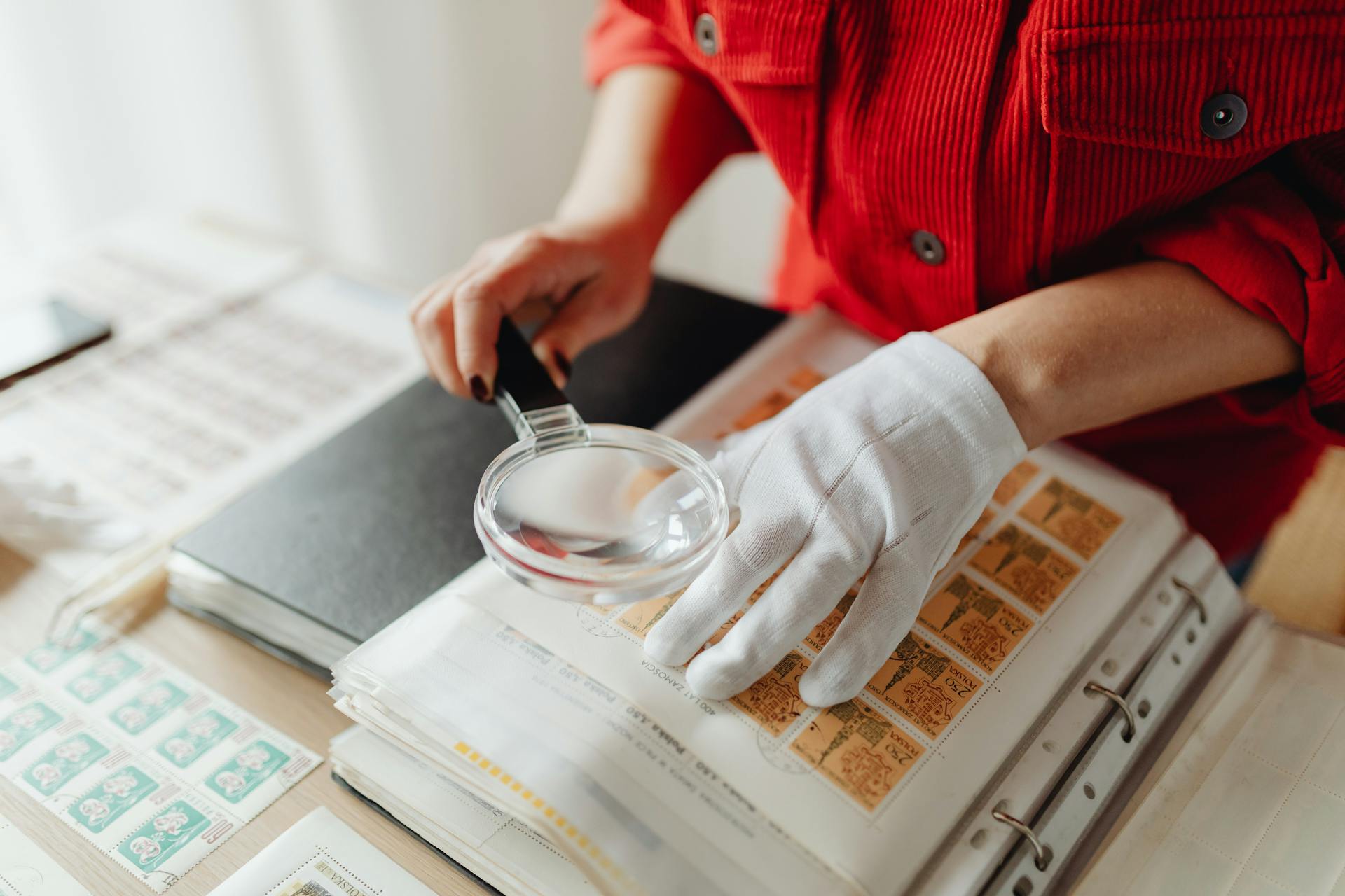 A Woman Using a Magnifying Glass on Postage Stamps