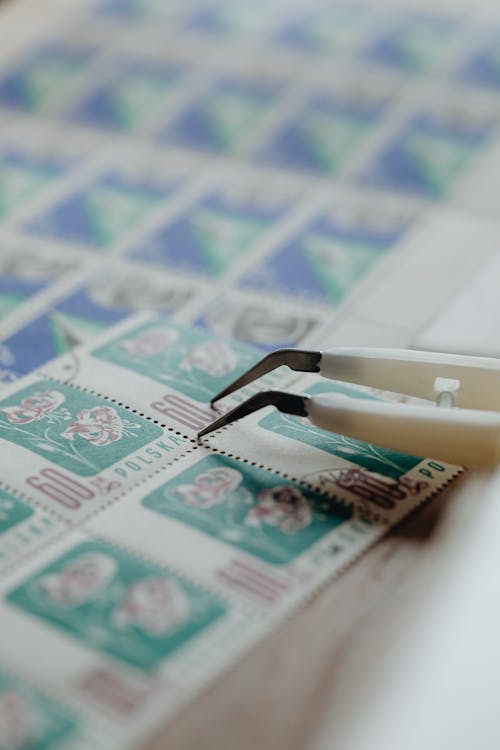 Tweezers on Sheets of Postage Stamps