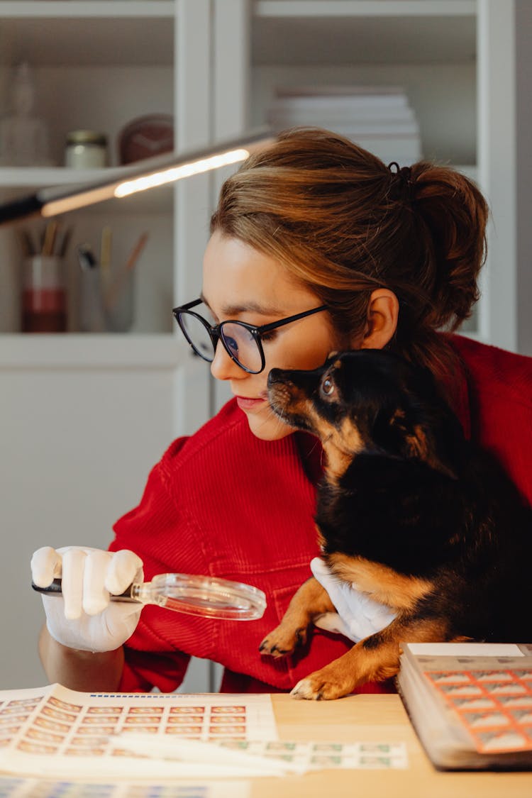 Woman With Dog Looking In Magnifier At Stamps