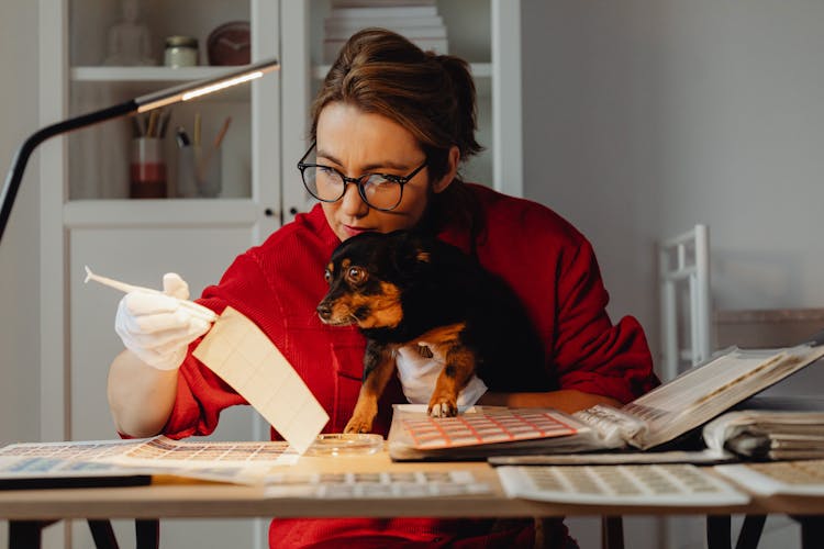 Woman With Dog Sitting At Table With Albums