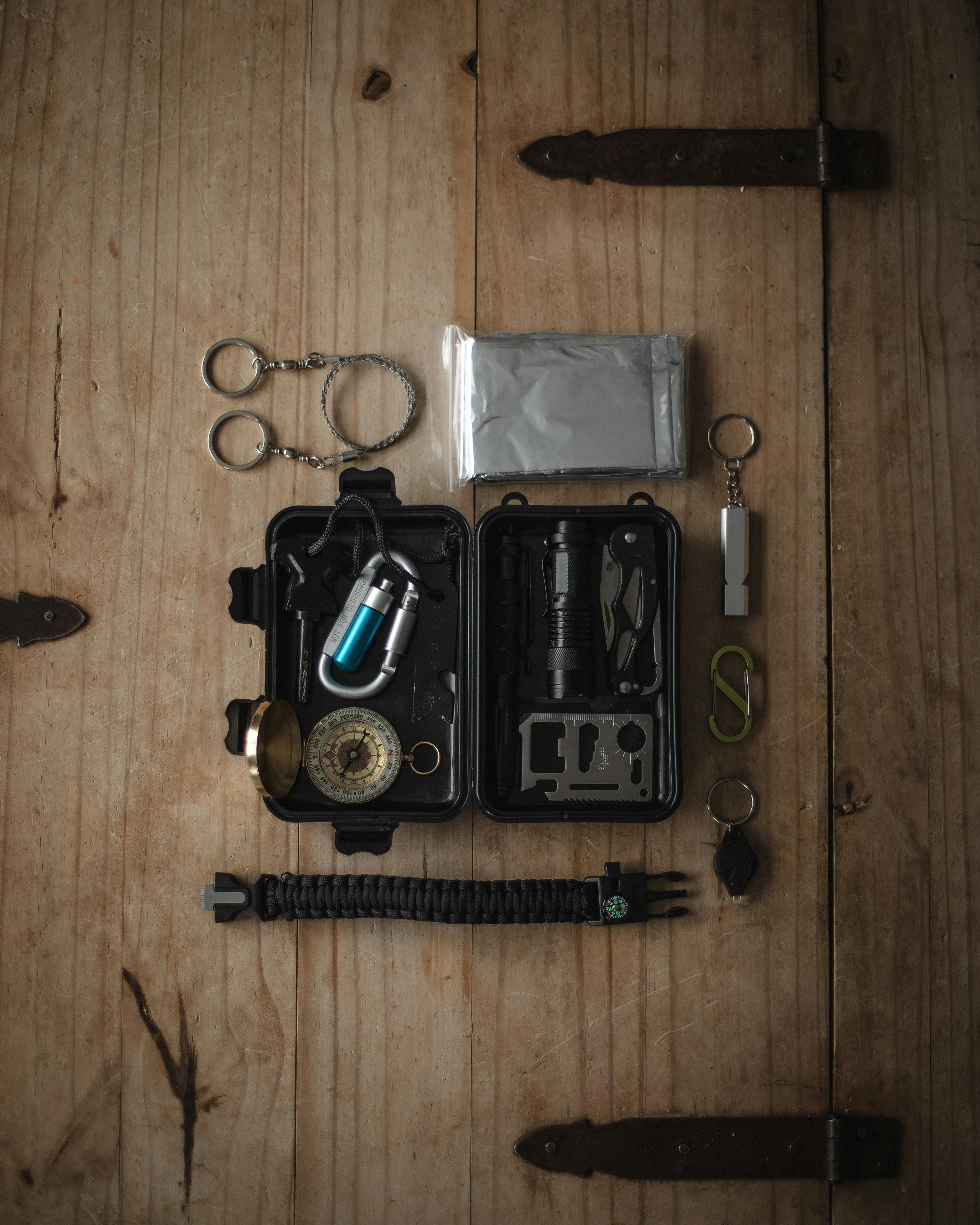Top view of a compact survival kit with essential tools on a wooden surface.