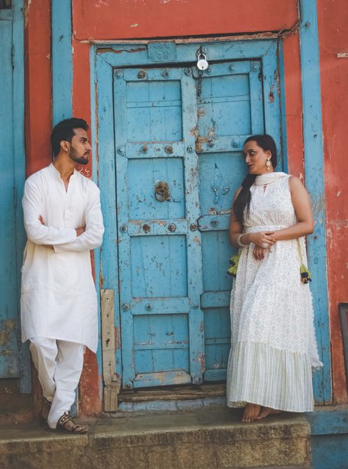 Free A couple poses in traditional Indian attire by an old colorful doorway, radiating cultural charm. Stock Photo