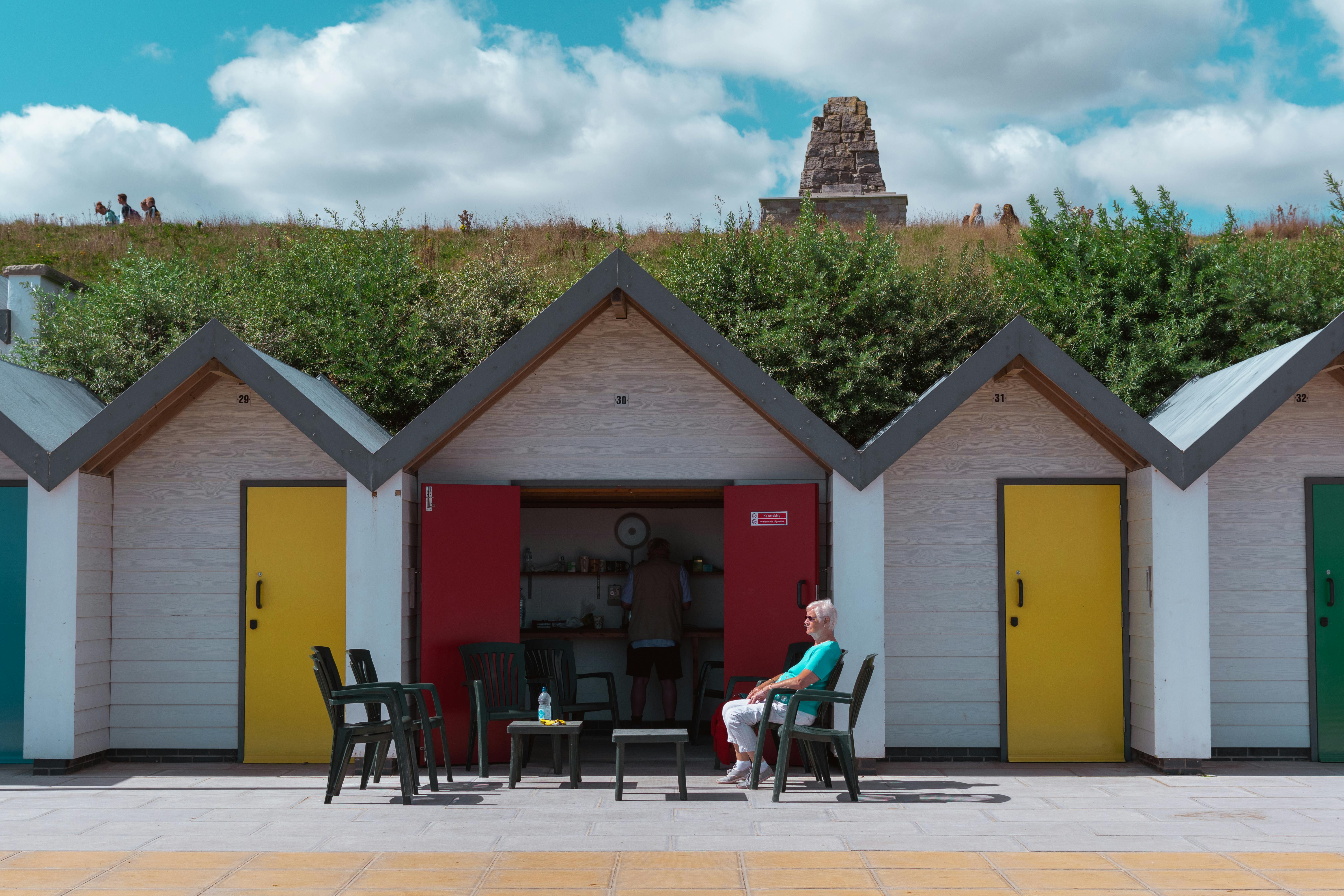 Vibrant beach huts with a senior woman enjoying a sunny day in Swanage, UK.