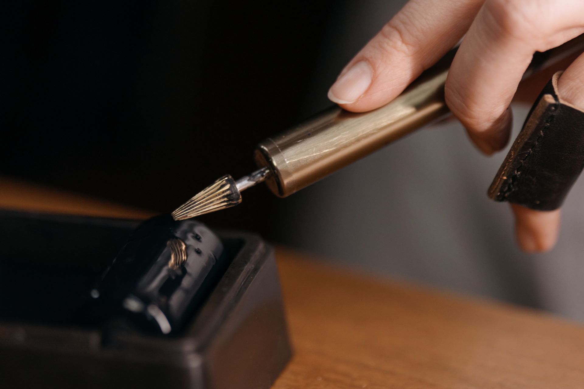 Close-up of Person Holding a Tool with a Sharp Iron Tip and Touching Paint with It to Use It on Leather