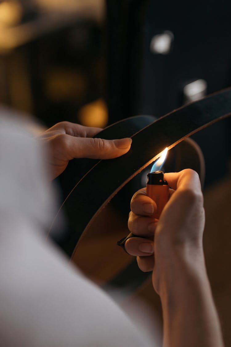 A Person Using A Lighter To Burn A Belt