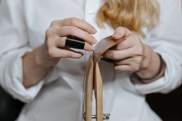 A Person Sewing A Brown Leather