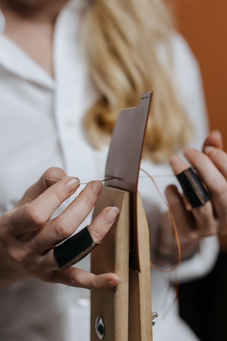 A Person Sewing A Leather