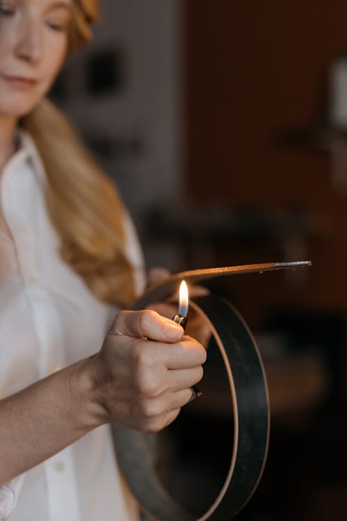 Woman Holding Lighter Flame over Leather Belt