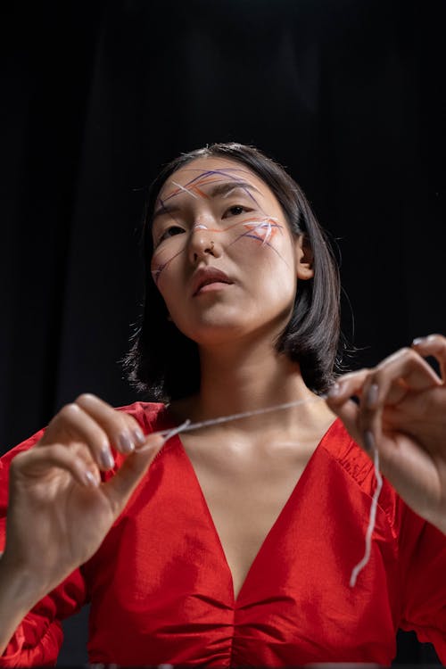 Woman with Face Paint Holding a Thread