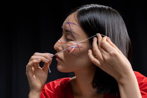 Woman in Red Shirt Applying Face Paint with a Thread