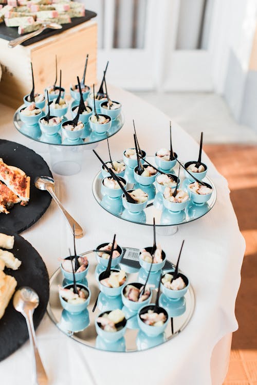 From above of cut octopus tentacles in small bowl served on mirror trays on round table near assorted dishes during banquet in restaurant