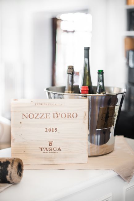 Wooden board placed near metal ice bucket with bottle of various alcohol drinks during event in restaurant