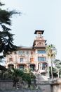 Low angle exterior of aged classic Villa Grock with arched windows and observation tower against cloudless blue sky in Imperia