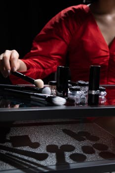 A woman in a red dress arranging makeup products on a reflective table. Elegant and chic.