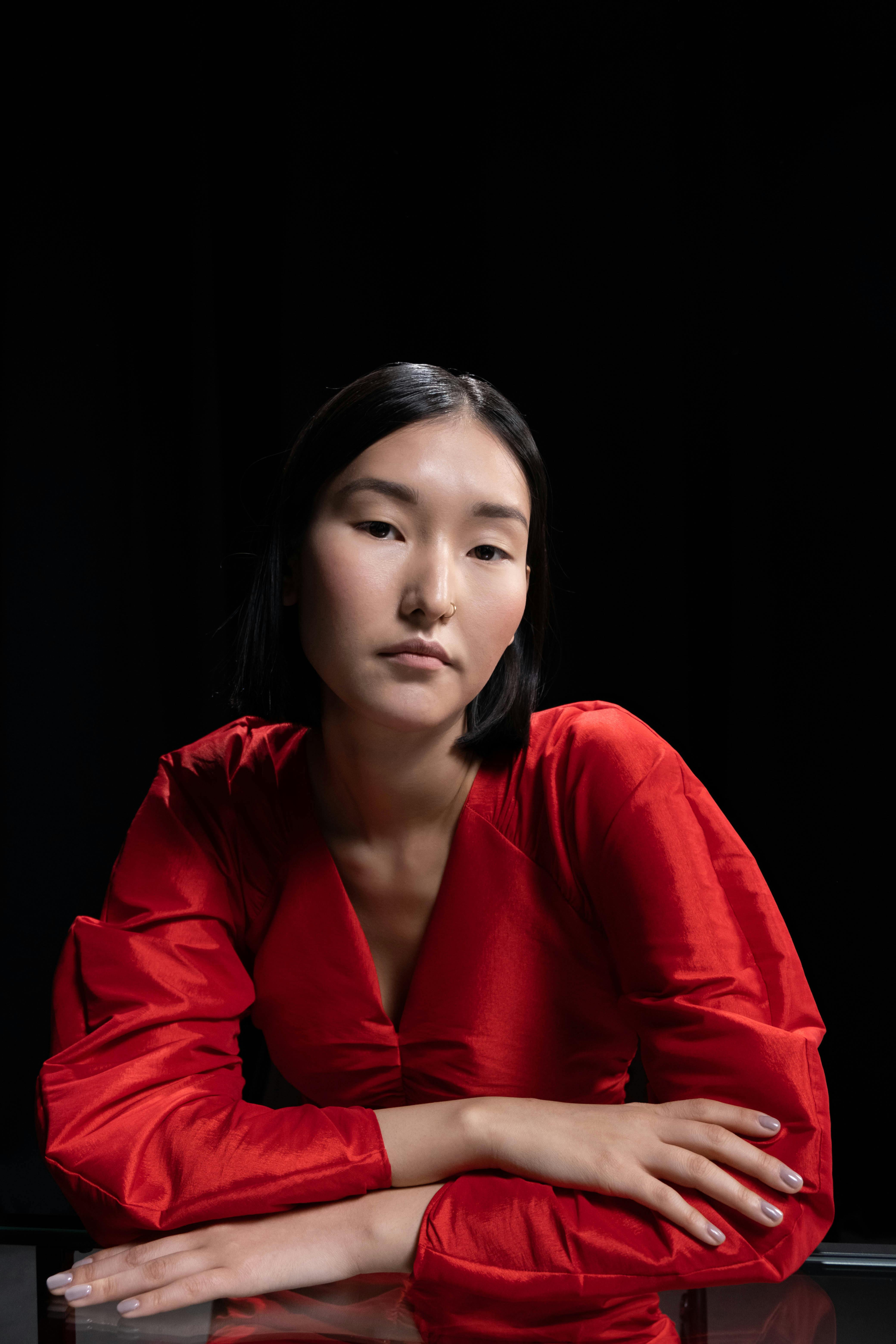 一位穿着鲜艳红色连衣裙、留着短发的女士优雅肖像，背景为黑色